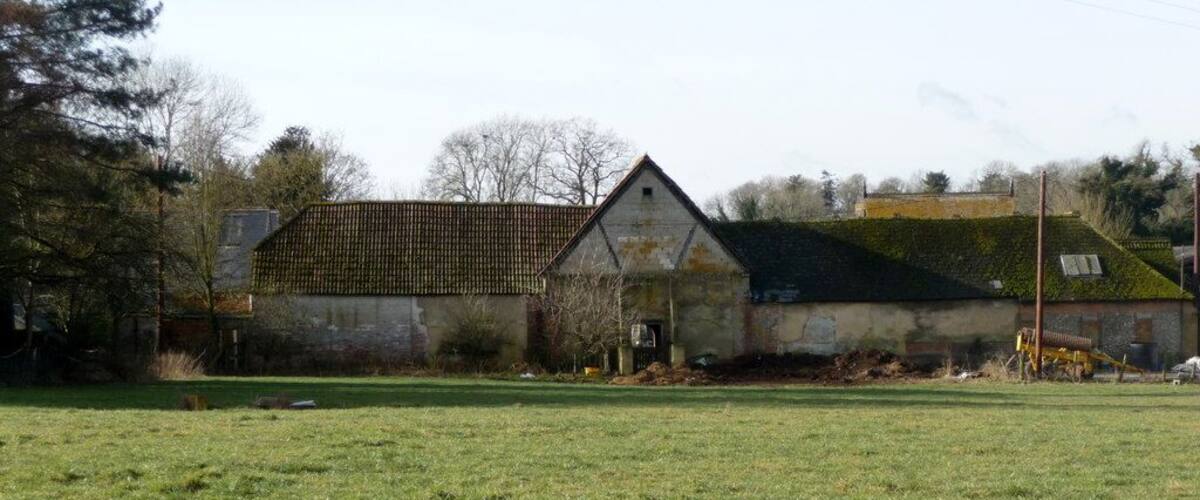 A large barn with a tiled roof and a smaller adjacent building with a green roof.