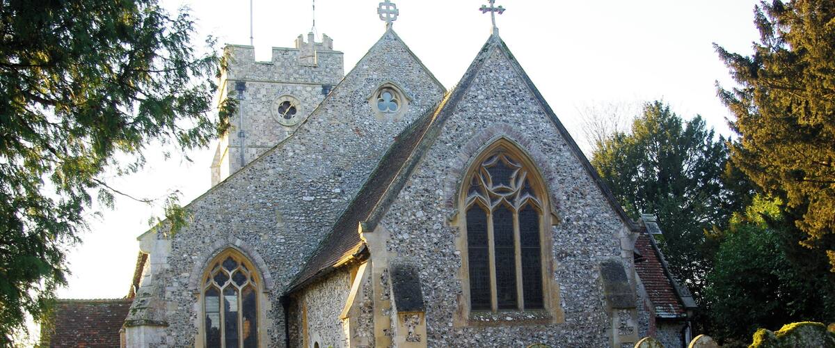 A historic church with a pointed steeple and a graveyard in front.
