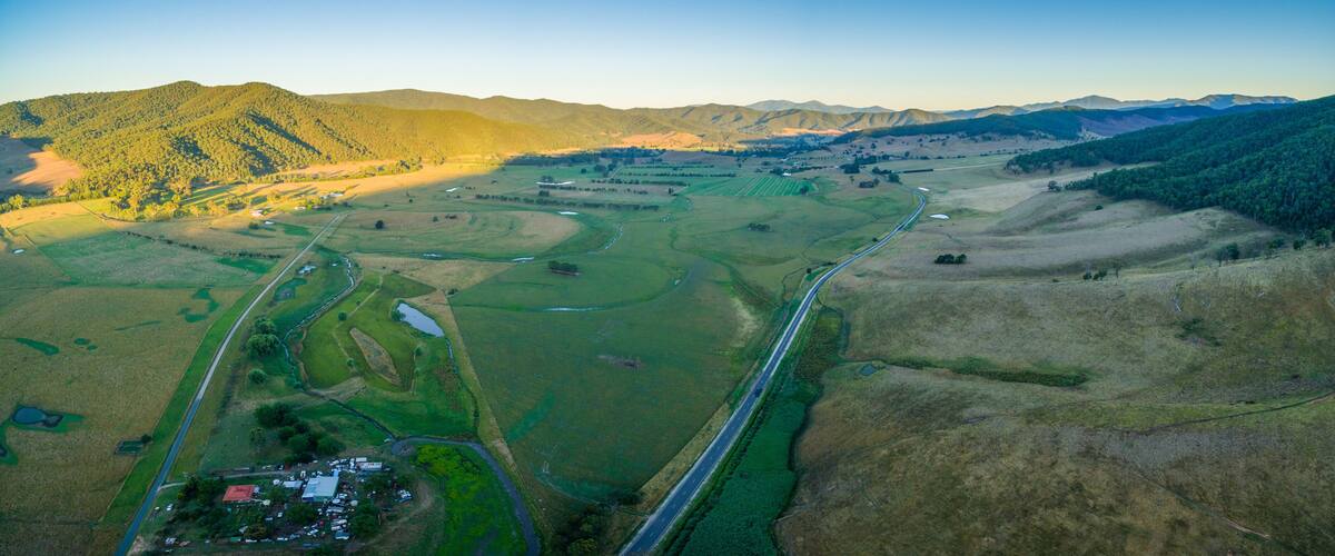 An aerial view of a rural landscape with fields, a winding road, and a small settlement.