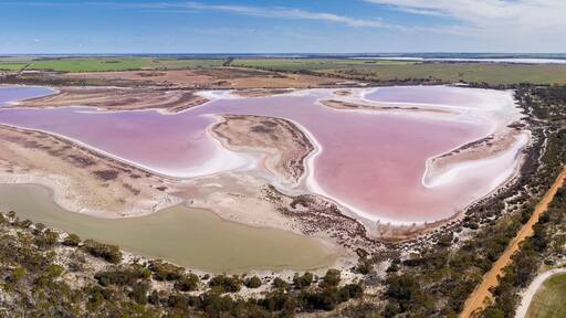 Aerial panoramic view of a large pink salt lake located next to highway 40 in the wheatbelt region of Western Australia