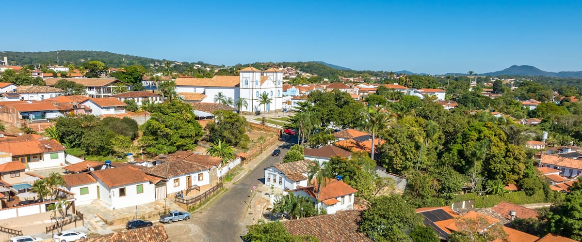 A town with red-tiled roofs, white buildings, and lush greenery.