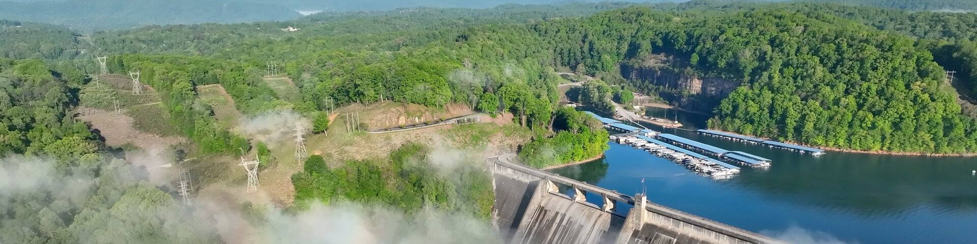 Norris Dam in Tennessee mountains at early morning sunlight beneath misty fog and clouds at daybreak