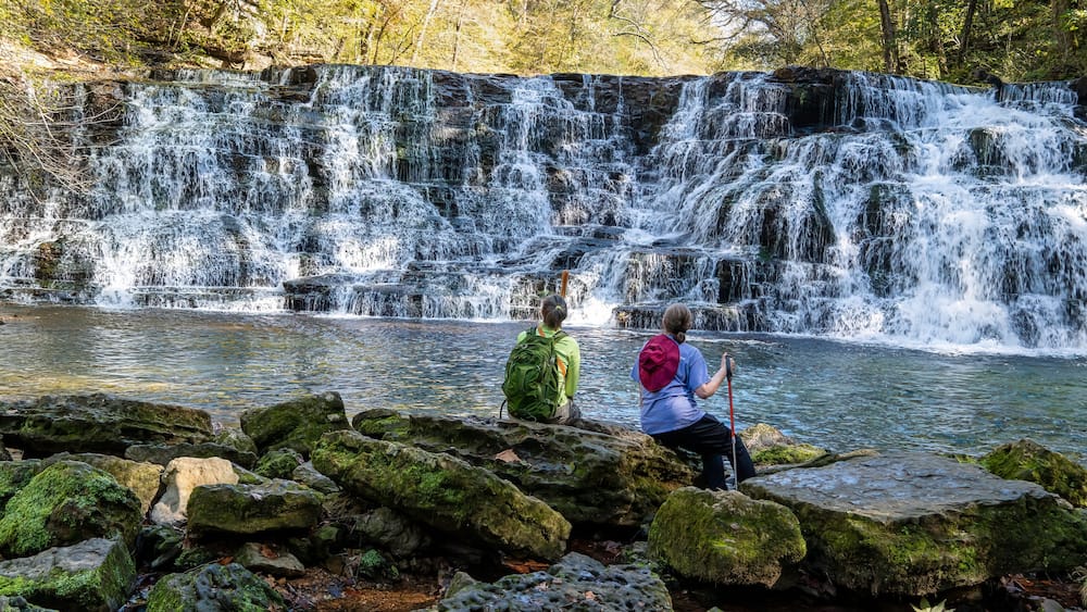 Two women hikers sitting on rocks at the base of Rutledge Falls enjoying the Beautiful view in Tennessee.