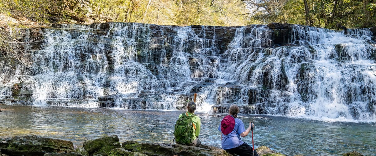 Two women hikers sitting on rocks at the base of Rutledge Falls enjoying the Beautiful view in Tennessee.