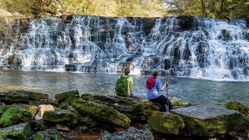 Two women hikers sitting on rocks at the base of Rutledge Falls enjoying the Beautiful view in Tennessee.