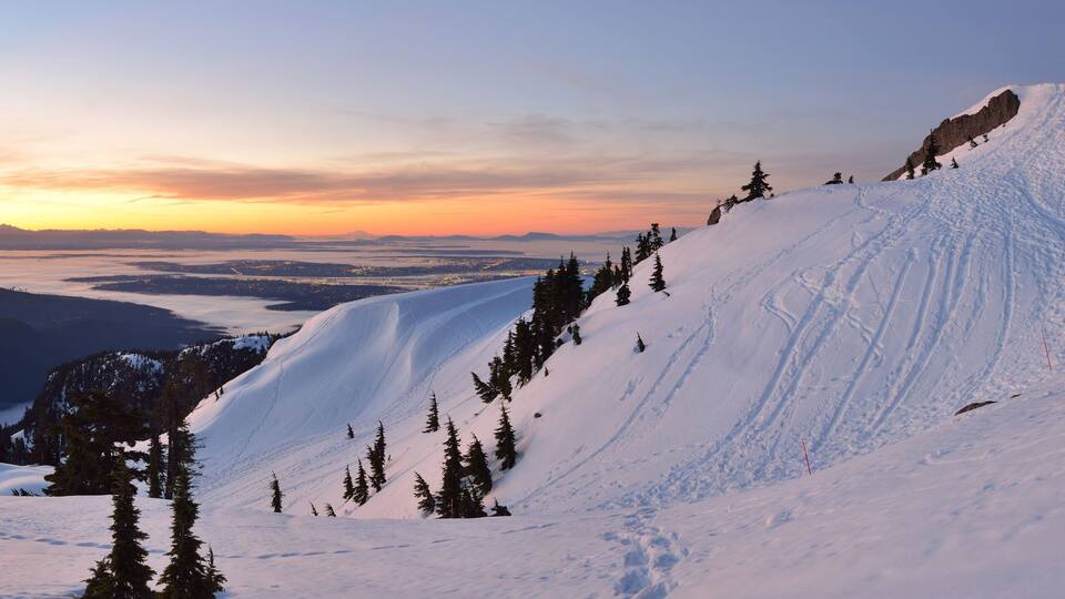 A snow-covered mountain with a clear sky and a sunset.