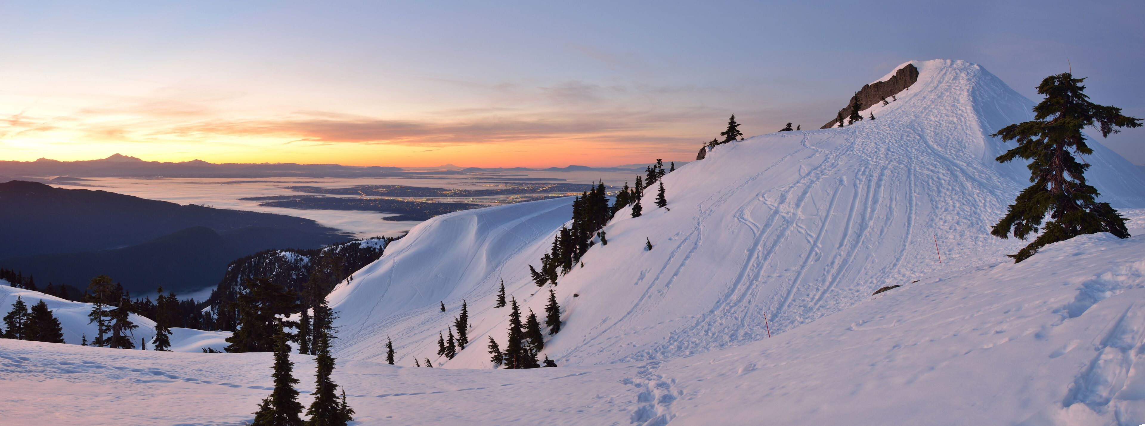 A snow-covered mountain with a clear sky and a sunset.