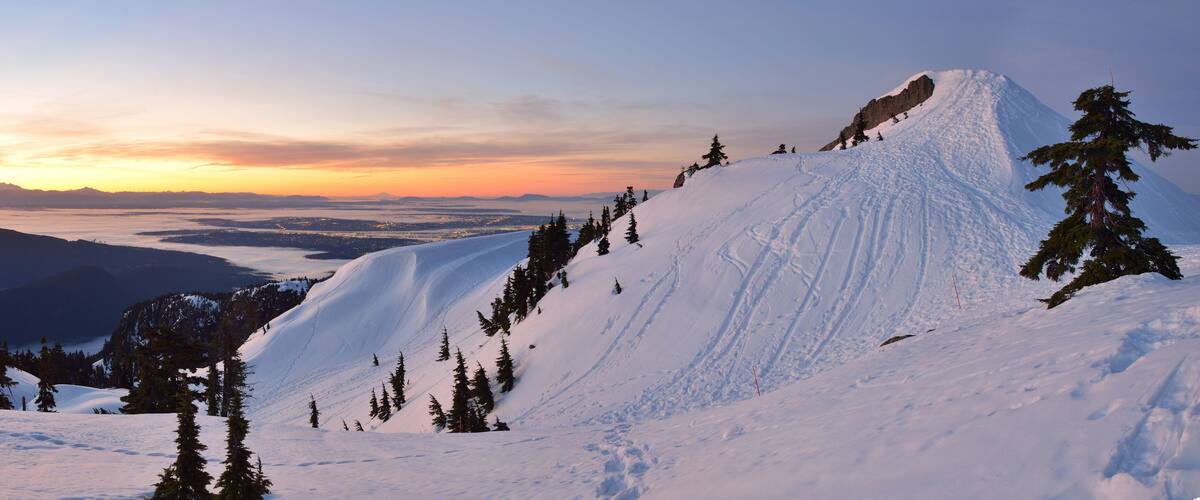 A snow-covered mountain with a clear sky and a sunset.