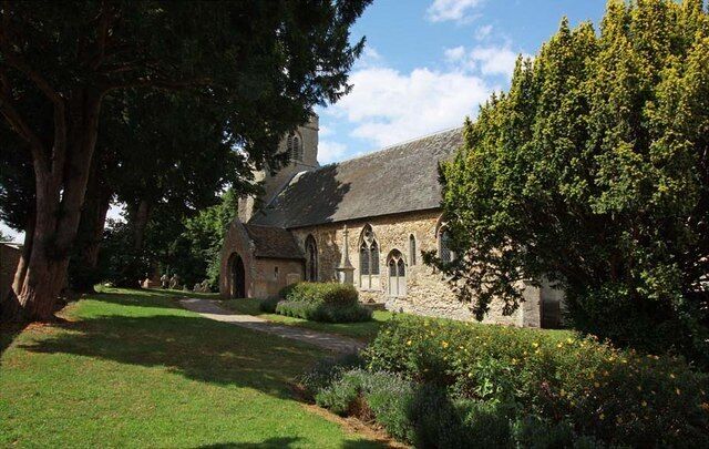 A stone church with a garden and large trees.