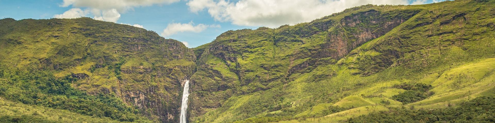 Un valle verde exuberante con una cascada y un caballo pastando.