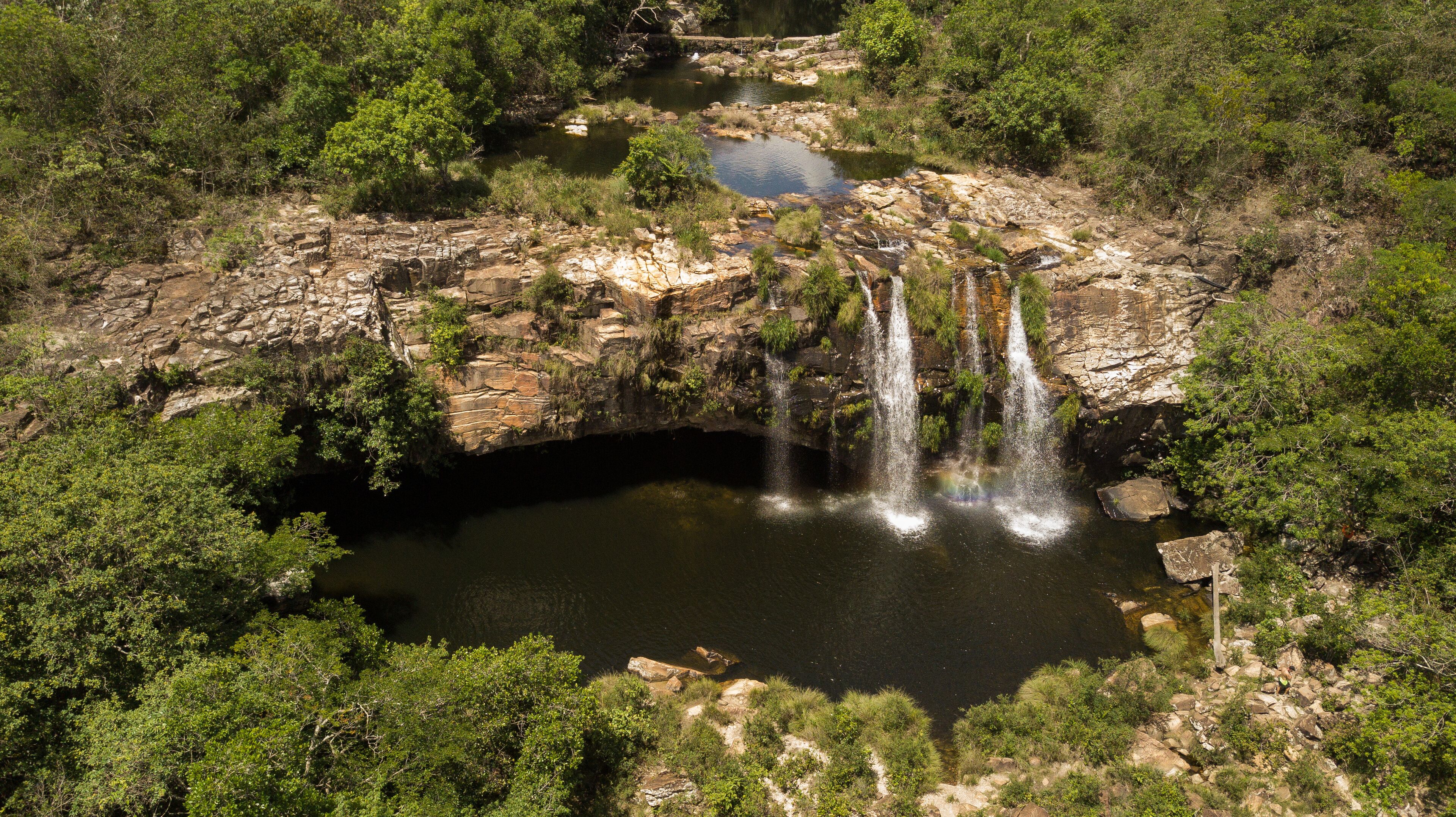 A waterfall cascading into a rocky pool surrounded by dense greenery.