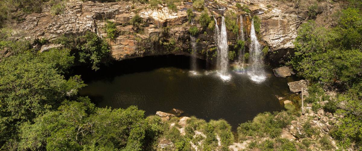 A waterfall cascading into a rocky pool surrounded by dense greenery.