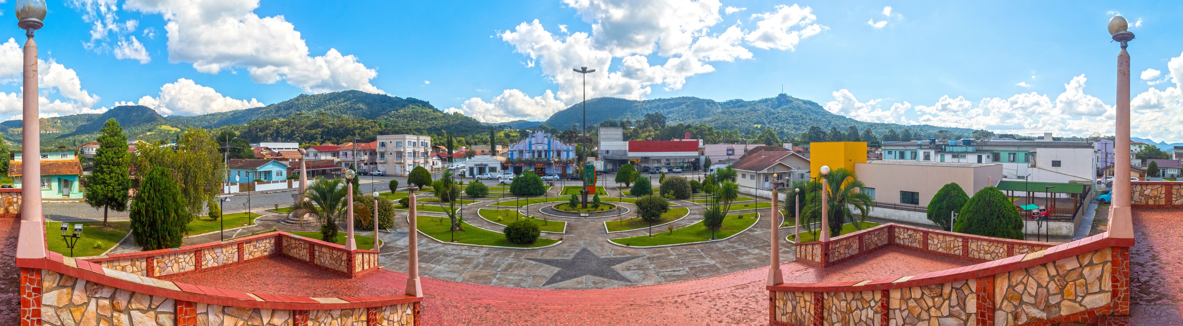 A town square with a star-shaped monument, surrounded by buildings and a mountain backdrop.