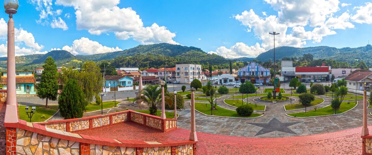 A town square with a star-shaped monument, surrounded by buildings and a mountain backdrop.