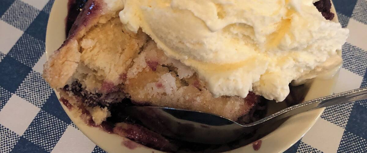 A slice of pie with ice cream on a plate.