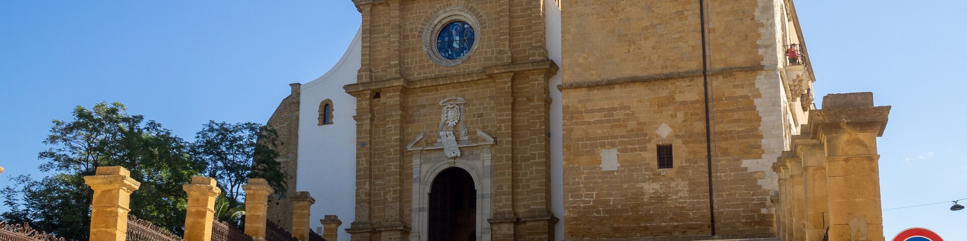 Una iglesia con un campanario y un reloj, que conduce a la entrada.