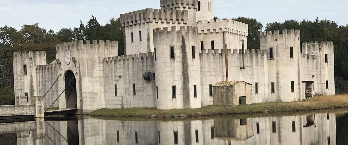 A castle with a moat and a clear reflection in the water.