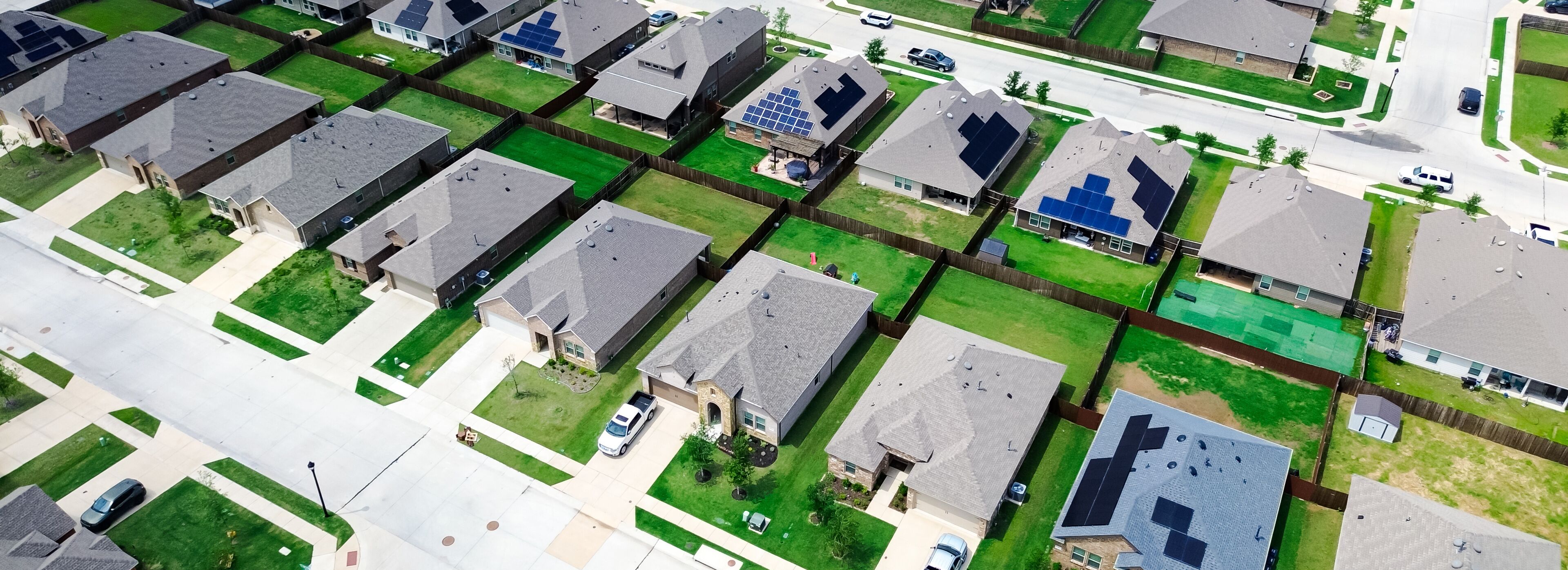 A residential area with houses, solar panels, and a street.