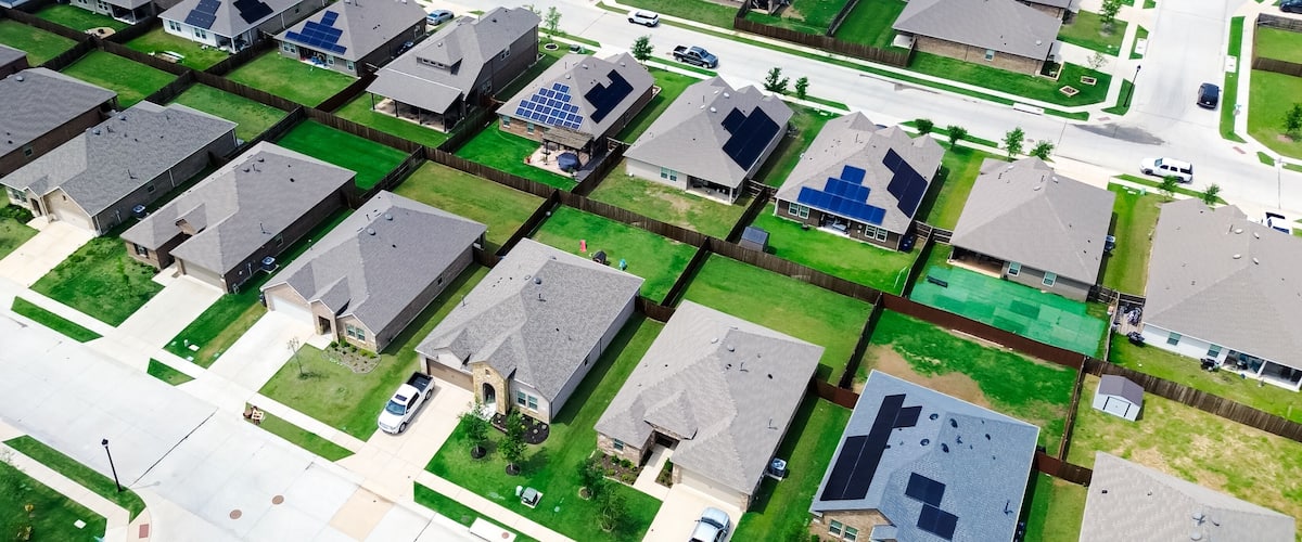 A residential area with houses, solar panels, and a street.
