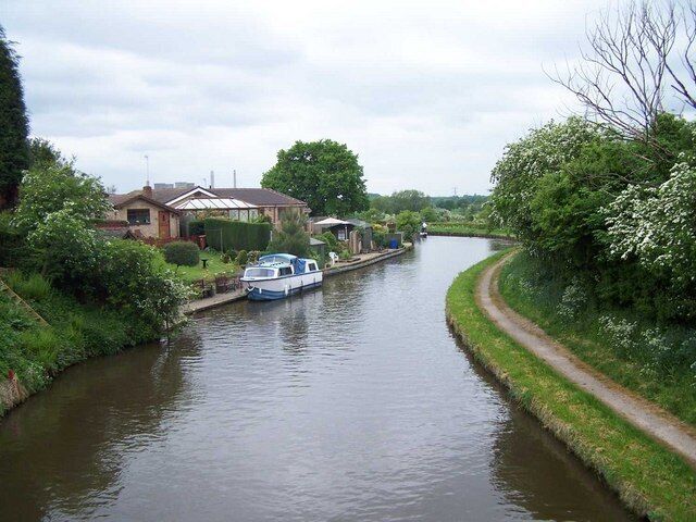 A narrow canal with a house and a boat docked on the left.