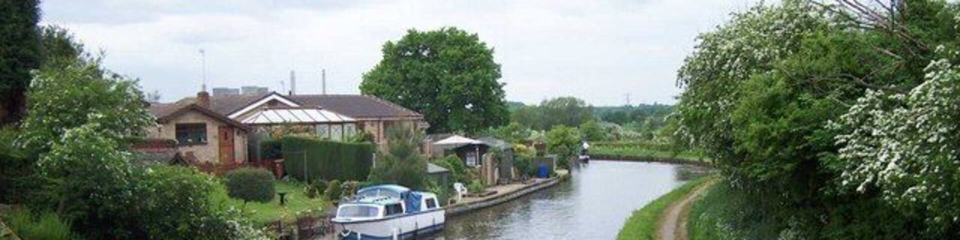 A narrow canal with a house and a boat docked on the left.