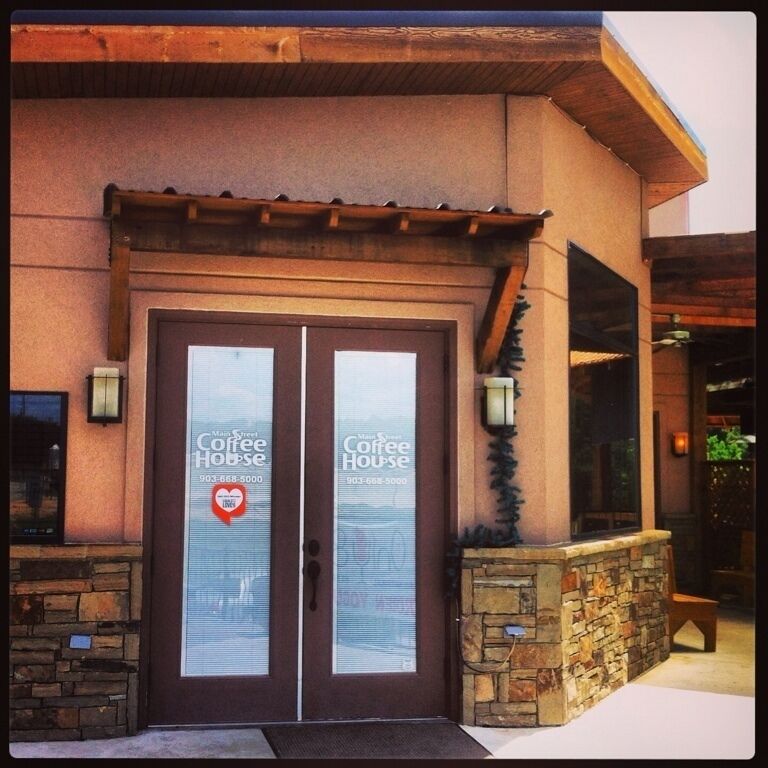 A building with a stone facade and a wooden pergola entrance.