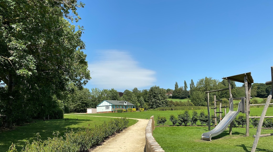 View from the entrance, of a park on, Calverley Lane, with a play area, and a building in the distance in, Horsforth, Leeds, UK