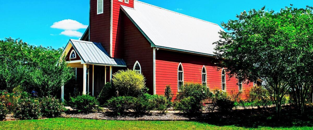 A red church with a white steeple and a small bell tower.