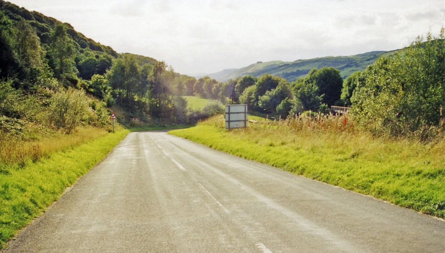 On A487 road down Afon Dulas near site of former Esgairgeiliog station. View SE, towards Machynlleth: the narrow-gauge Corris Railway, Machynlleth - Aberllefeni, used to run down this valley until it closed 21/8/48, having lost its passenger service 1/1/31. The heritage Corris Railway is a few miles further back.