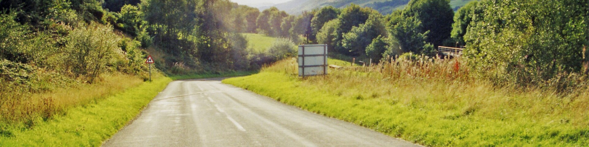 On A487 road down Afon Dulas near site of former Esgairgeiliog station. View SE, towards Machynlleth: the narrow-gauge Corris Railway, Machynlleth - Aberllefeni, used to run down this valley until it closed 21/8/48, having lost its passenger service 1/1/31. The heritage Corris Railway is a few miles further back.