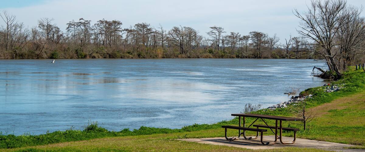 A calm river with a picnic table and grassy banks.