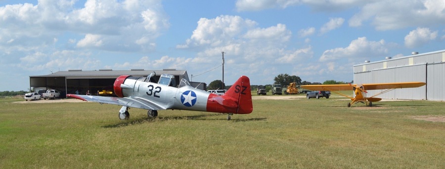 A visiting North American T-6G at Old Kingsbury Aerodrome, with a newly-acquired Piper J-3 Cub in the background.