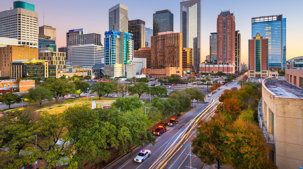 A city skyline with modern skyscrapers, a busy street with cars, and trees lining the roads.