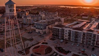 Aerial view of the Little Elm water tower standing tall against a fiery sunset casting a warm glow over the buildings, Little Elm, Texas, United States.
