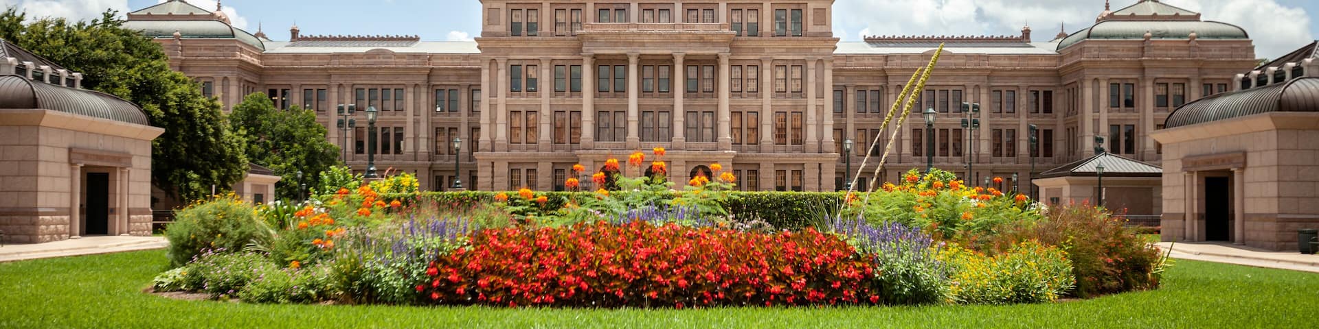 Texas State Capitol in Austin, Texas on a sunny summer day with colorful flowers in the front yard