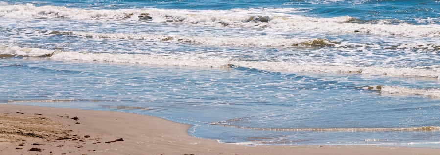 Una playa con olas suaves lamiendo la orilla.