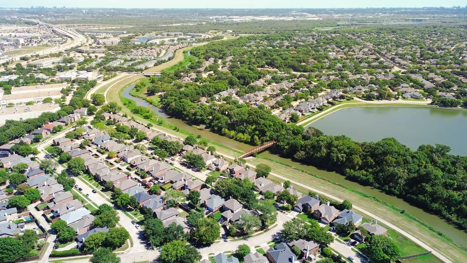 A residential area with houses, a river, and a bridge.