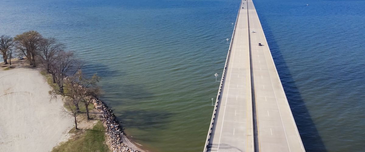 Aerial view rock wall shoreline lakefront and Two Mile Bridge over Lake Tawakoni to horizontal line in Quinlan, Texas