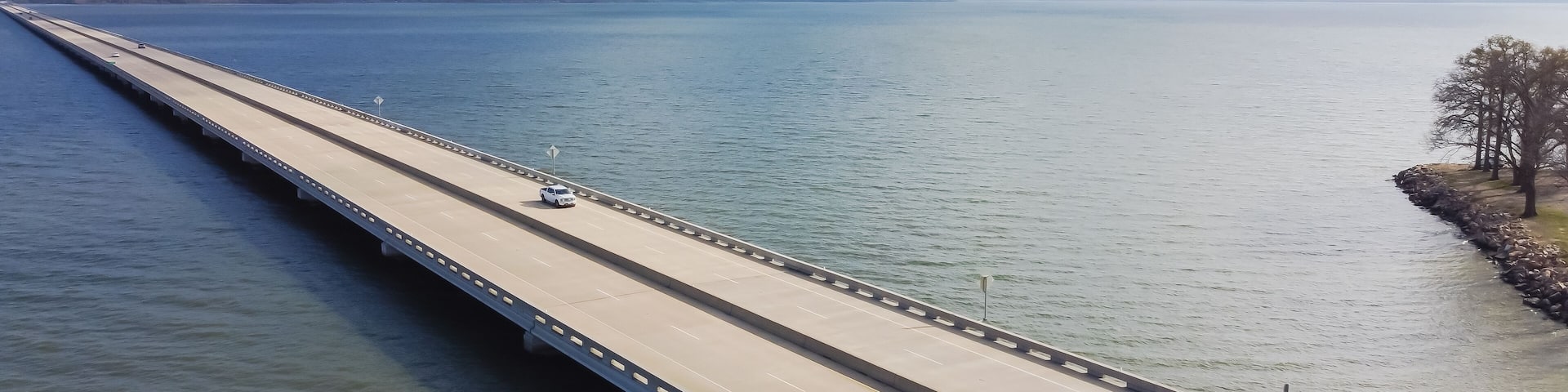 Panoramic Aerial view rock wall shoreline lakefront and Two Mile Bridge over Lake Tawakoni to horizontal line in Quinlan, Texas