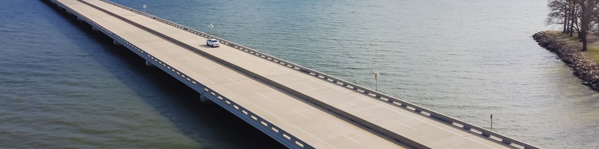 Panoramic Aerial view rock wall shoreline lakefront and Two Mile Bridge over Lake Tawakoni to horizontal line in Quinlan, Texas