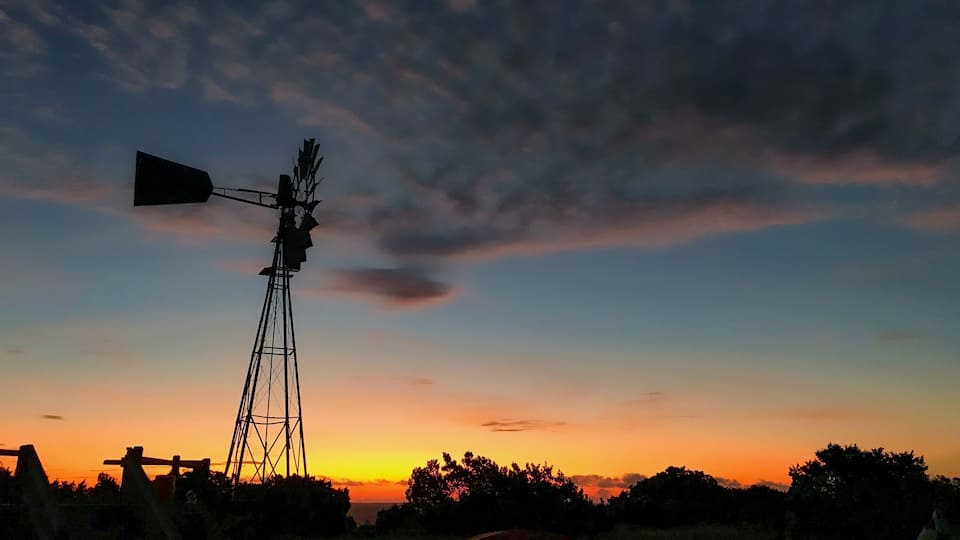 A windmill silhouetted against a sunset sky.
