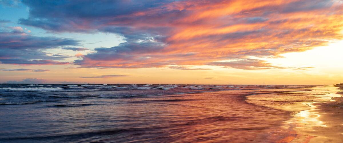 A beach with waves at sunset.
