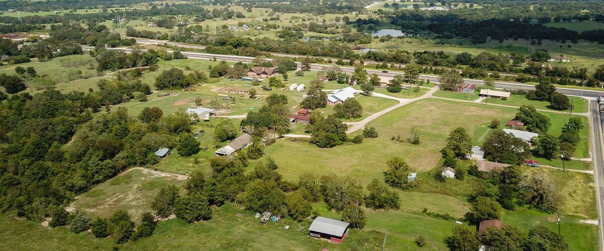 An aerial view of a rural area with scattered houses, fields, and a highway.