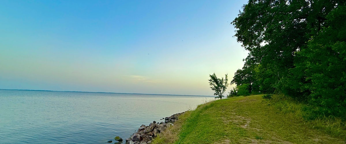 A calm lake with a rocky shoreline and grassy banks.