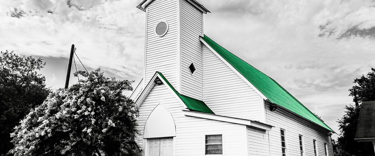 A church with a steeple and a green roof.