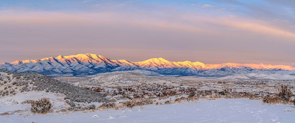 A snow-covered mountain range with a town in the foreground.