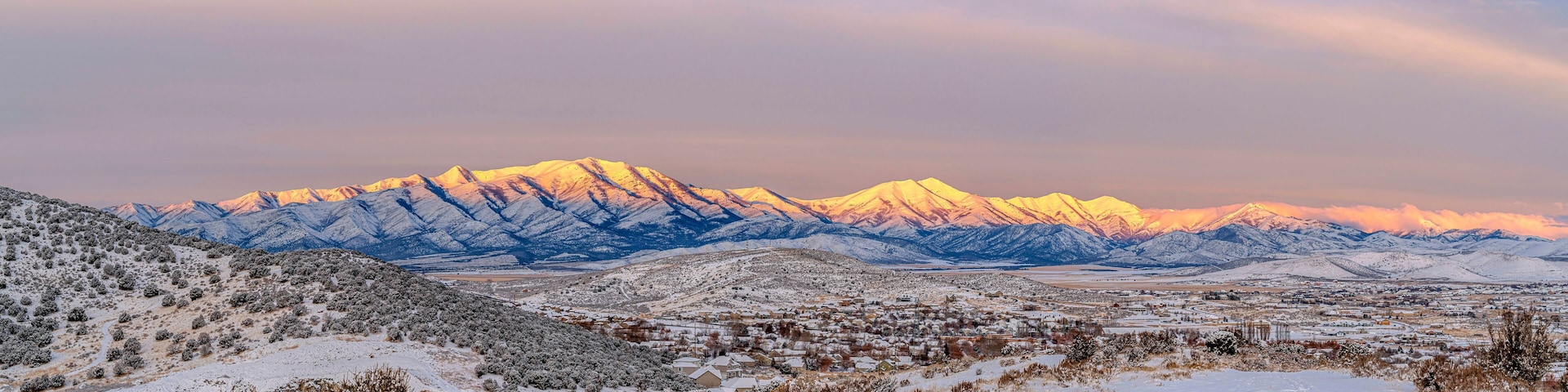 A snow-covered mountain range with a town in the foreground.