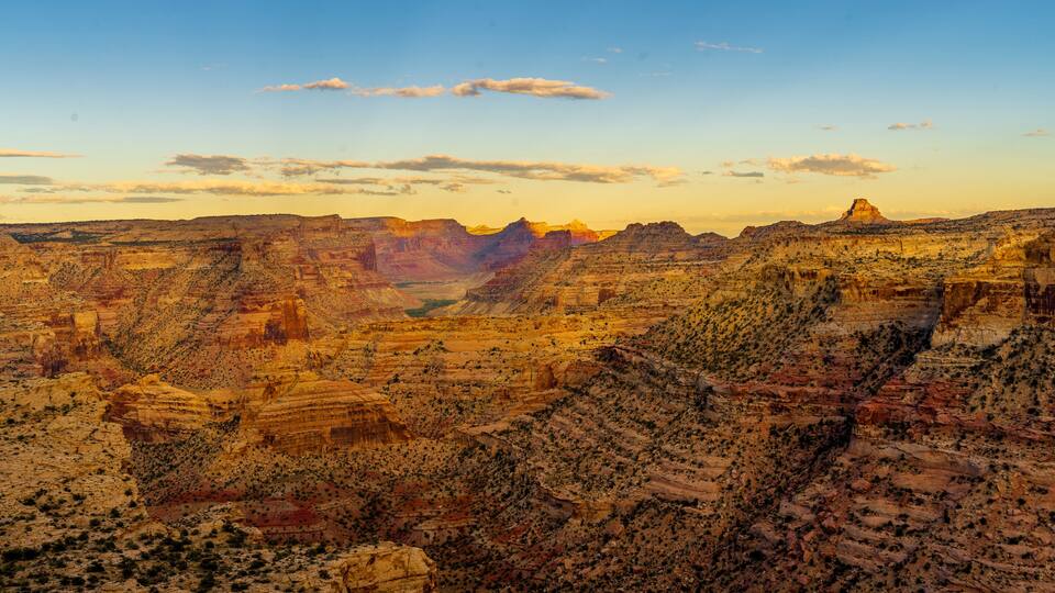 A canyon landscape with layered rock formations and sparse vegetation.