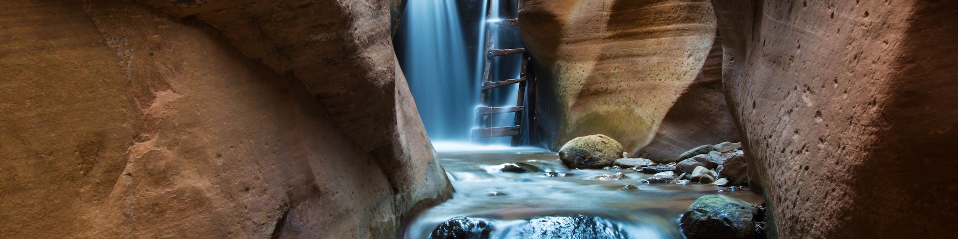 A narrow canyon with a waterfall.