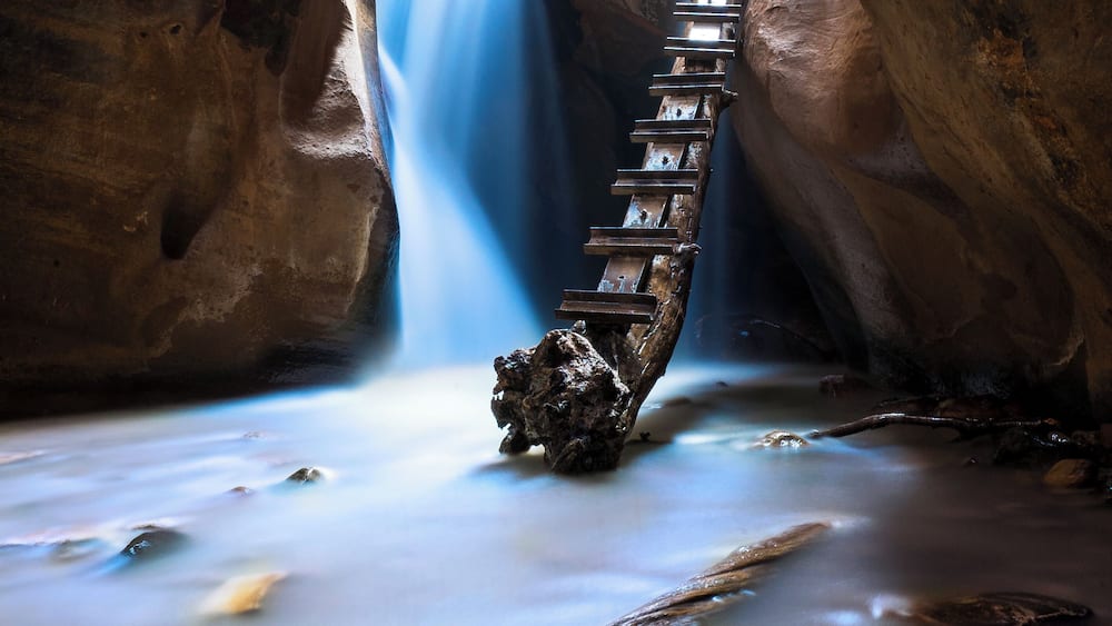 A wooden staircase descending into a canyon with a waterfall.